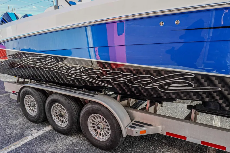 Slide: The Image of 2024 Renegade 38 Open boat on trailer, featuring sleek blue and carbon fiber design. - 8