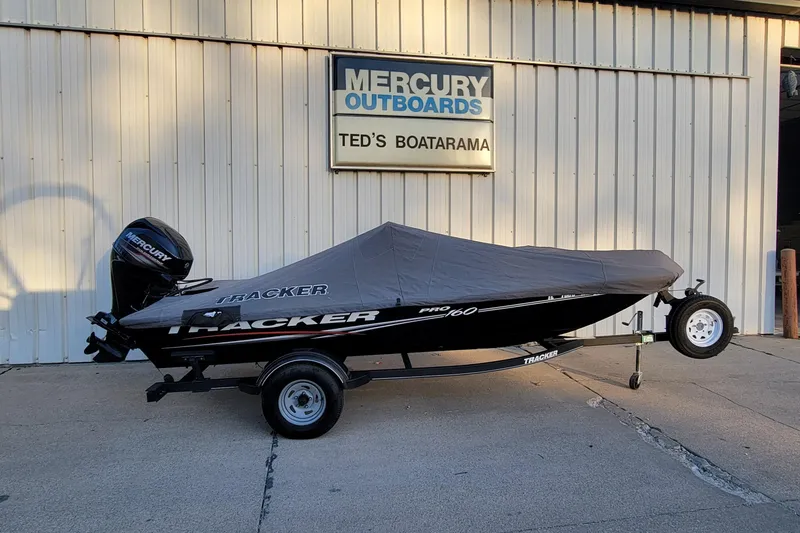 Slide: The Image of 2018 Bass Tracker Pro 16 boat with cover, parked outside Mercury Outboards dealership. - 2