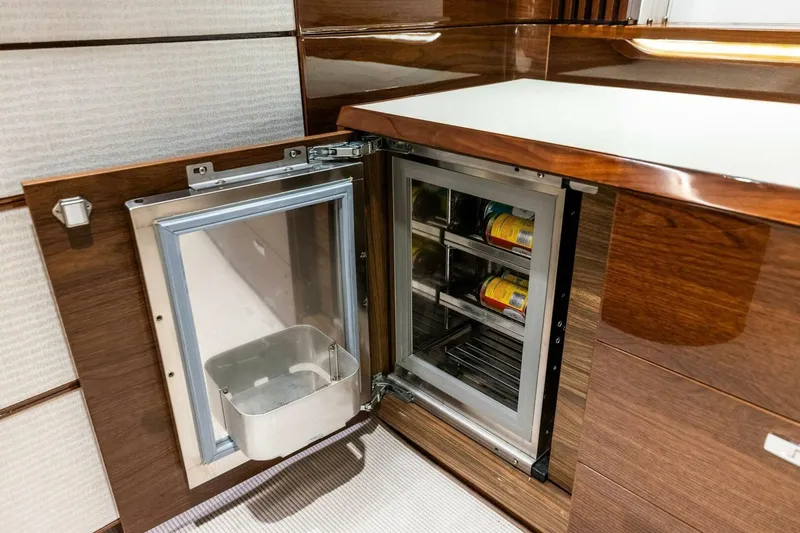 Slide: The Image of Luxury yacht Princess X80 2024 interior with open mini fridge and wooden cabinetry. - 85
