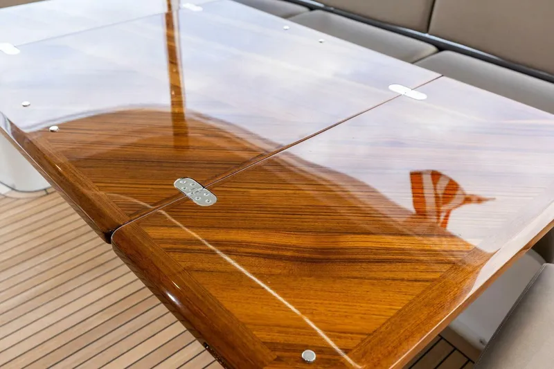 Slide: The Image of Polished wooden table on 2024 Princess X80 yacht deck, reflecting sky and flag. - 89
