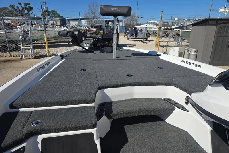 Slide: The Image of 2023 Skeeter ZXR19 boat with spacious deck and modern design in a marina setting. - 11