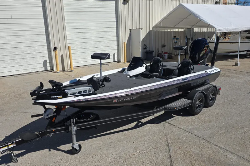 Slide: The Image of 2023 Skeeter ZXR19 fishing boat on trailer, parked outside a garage. - 8