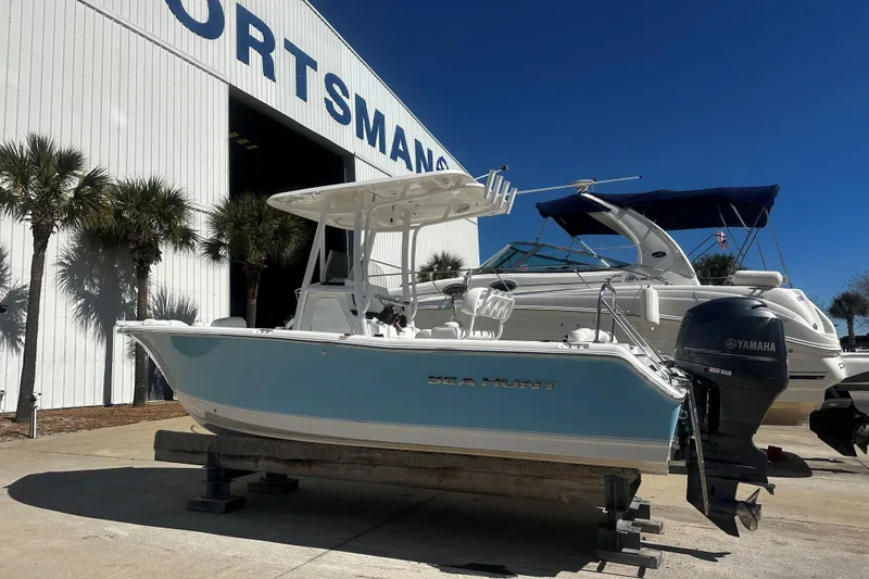 The Image of 2015 Sea Hunt Ultra 211 boat displayed outside dealership with palm trees and clear sky. - 1