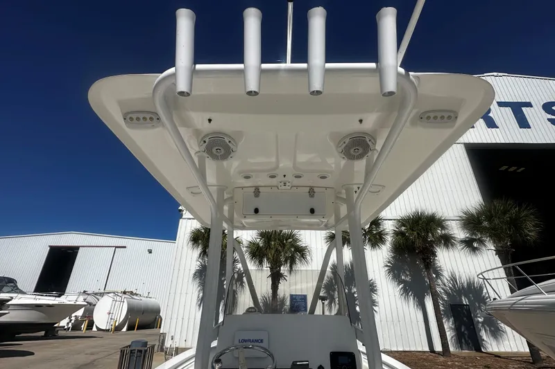 Slide: The Image of 2015 Sea Hunt Ultra 211 boat with T-top and rod holders, docked near a white building. - 6