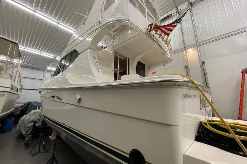 Slide: The Image of 2005 Silverton 34 Convertible yacht in indoor storage, featuring sleek design and American flag. - 2