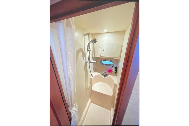 Slide: The Image of Compact shower area in 2005 Silverton 34 Convertible boat, featuring modern fixtures and porthole. - 38
