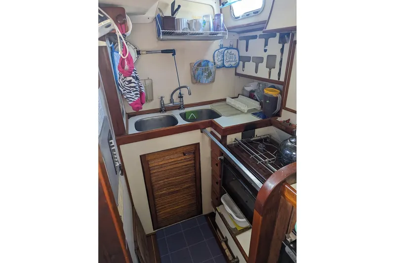 Slide: The Image of Compact kitchen in a 1990 Bruce Roberts Mauritius Ketch sailboat, featuring a sink and stove. - 7