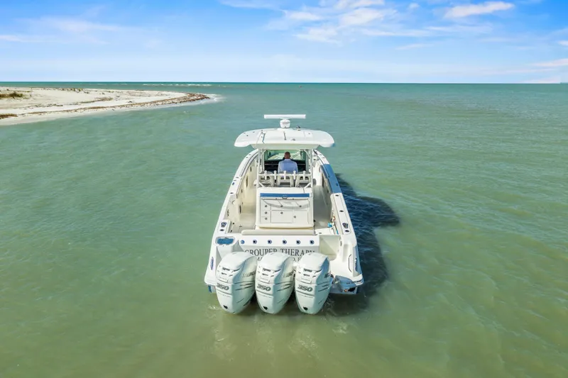 Slide: The Image of 2017 Boston Whaler 350 Outrage cruising near a sandy shoreline under a clear blue sky. - 4