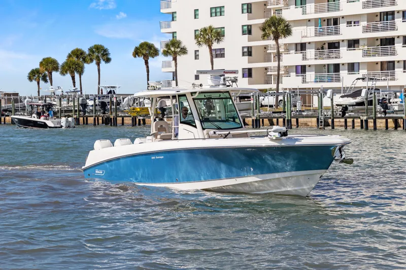 Slide: The Image of 2017 Boston Whaler 350 Outrage boat cruising near waterfront buildings and palm trees. - 44