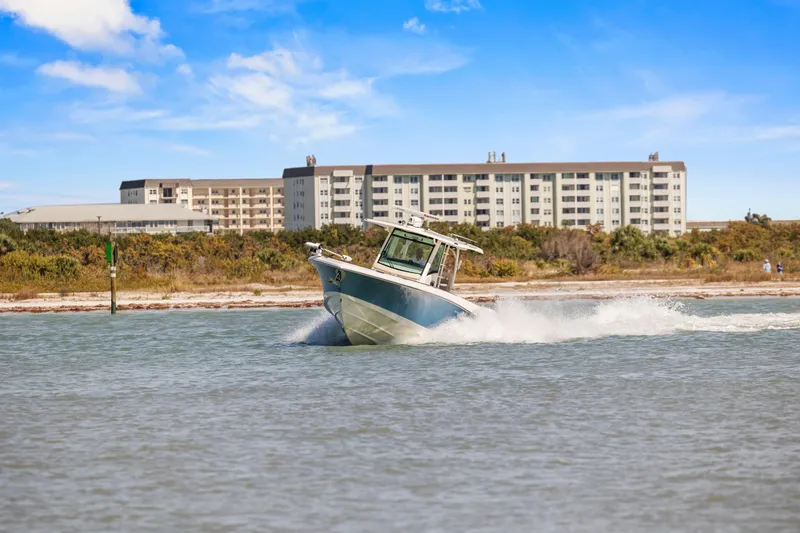 Slide: The Image of 2017 Boston Whaler 350 Outrage cruising near coastal buildings under blue sky. - 51