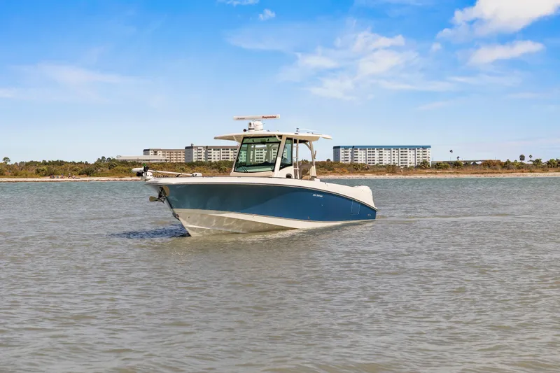 Slide: The Image of 2017 Boston Whaler 350 Outrage boat on calm water with buildings in the background. - 53
