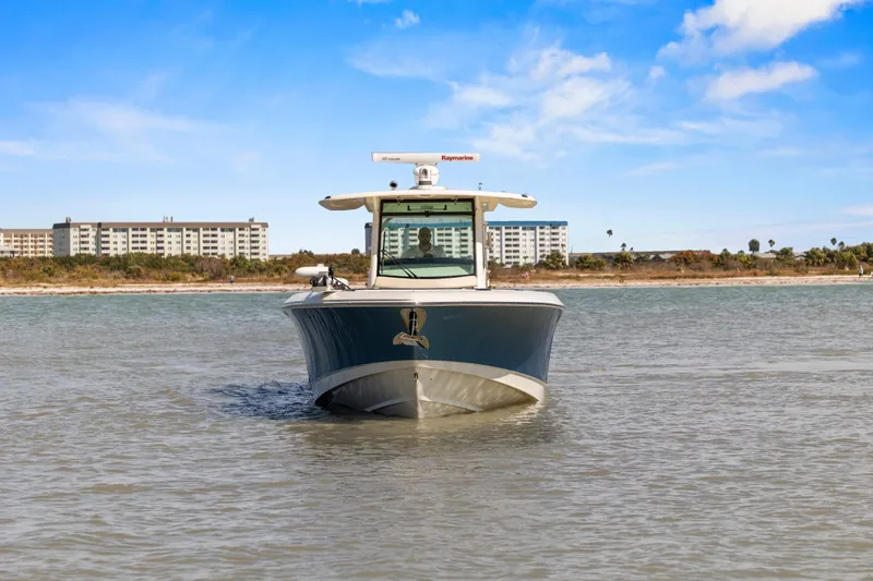 Slide: The Image of 2017 Boston Whaler 350 Outrage boat on calm water with buildings in the background. - 54