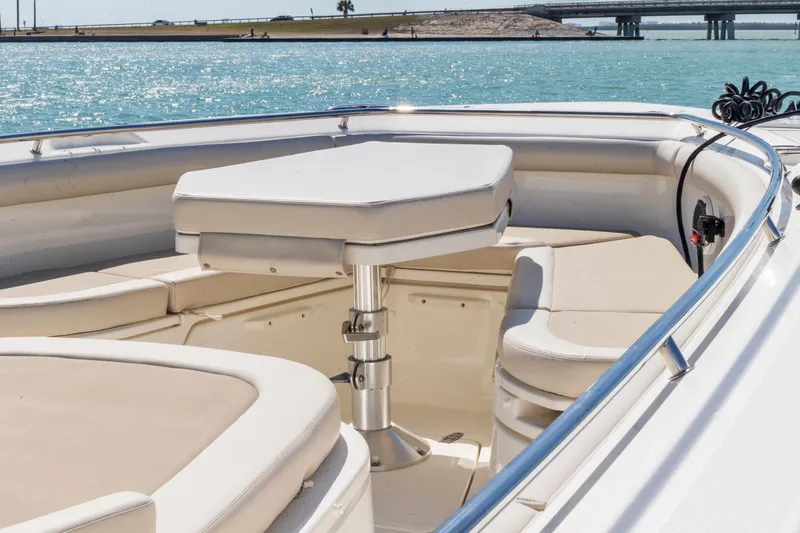 Slide: The Image of 2017 Boston Whaler 350 Outrage boat interior with seating and table, near a scenic waterfront. - 9