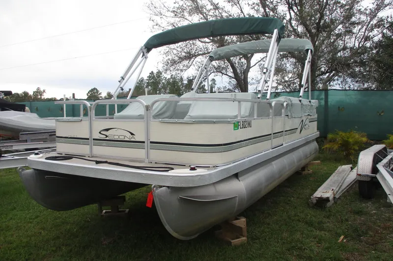 The Image of 2005 Bennington 21 pontoon boat with canopy, parked on grass. - 1