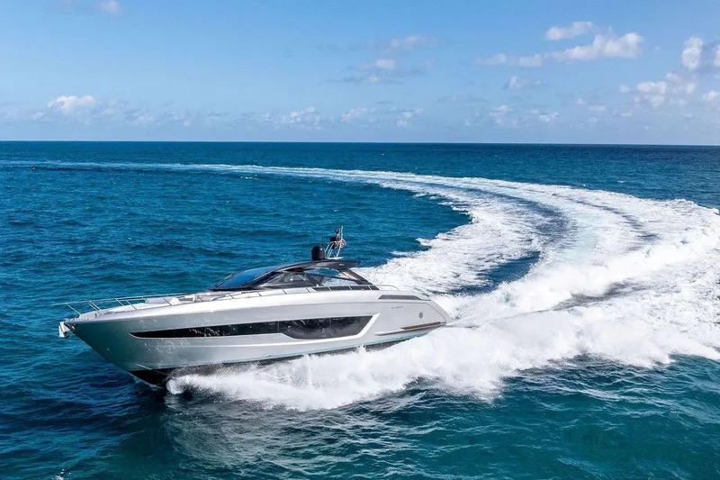 The Image of 2023 Riva 68 Diable yacht cruising on open sea with city skyline backdrop. - 0