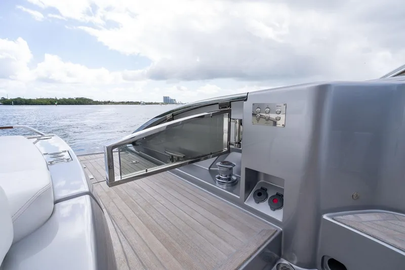 Slide: The Image of 2023 Riva 68 Diable yacht deck with open storage compartment, overlooking serene water. - 28