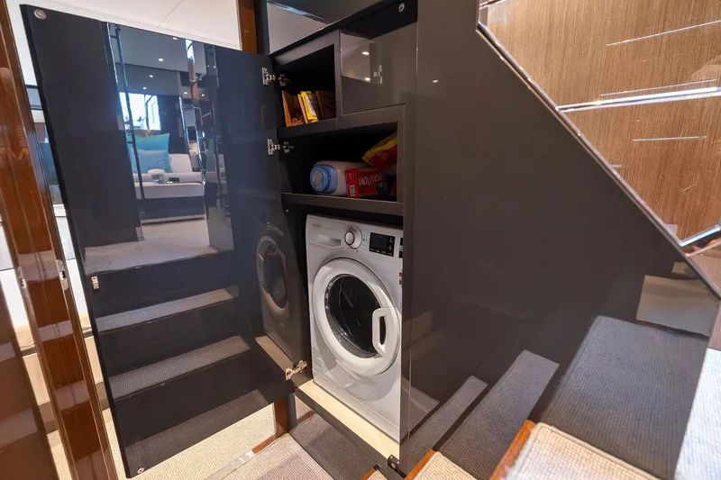 Slide: The Image of Laundry area inside 2023 Riva 68 Diable yacht, featuring a washing machine and storage. - 51