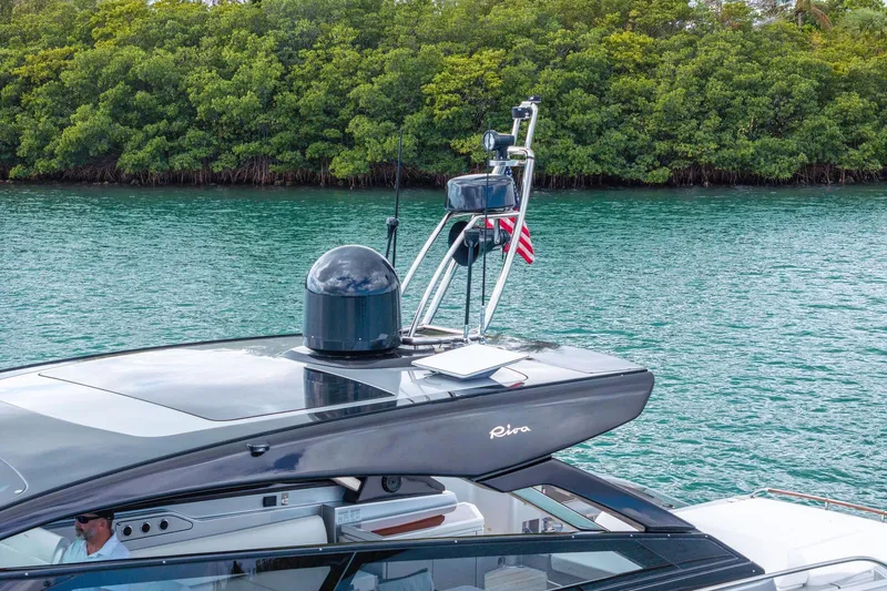 Slide: The Image of 2023 Riva 68 Diable yacht cruising on a serene waterway with lush greenery. - 9