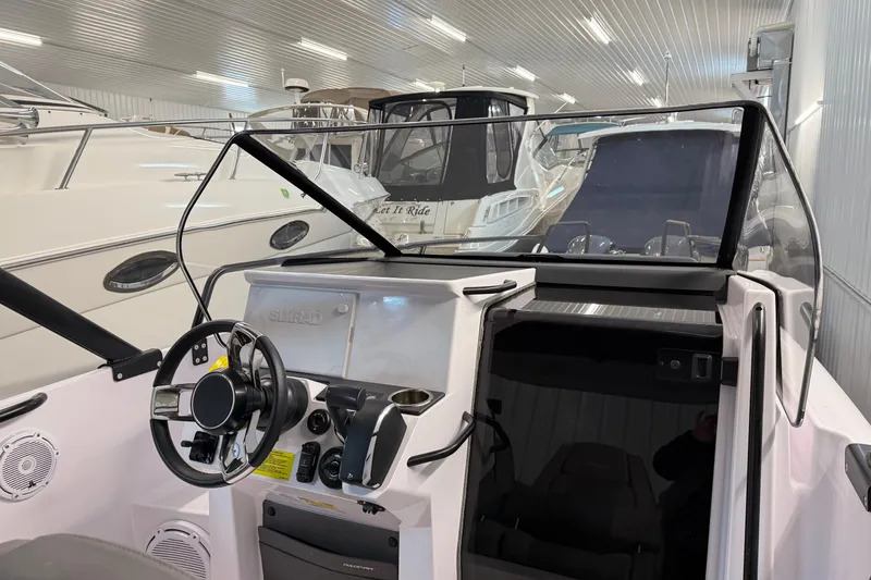 Slide: The Image of 2023 Axopar 25 Cross Bow interior with steering wheel and dashboard in a boat showroom. - 19