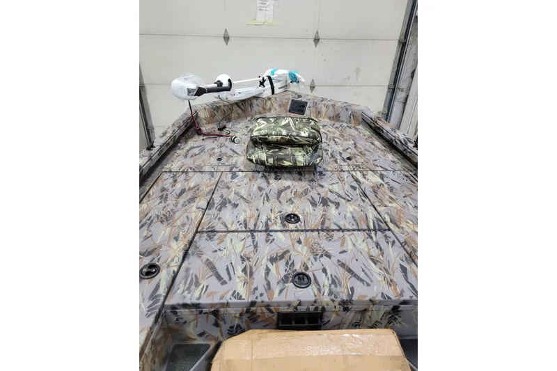 Slide: The Image of 2025 Ranger RB210 boat with camouflage deck and equipment in a garage setting. - 20