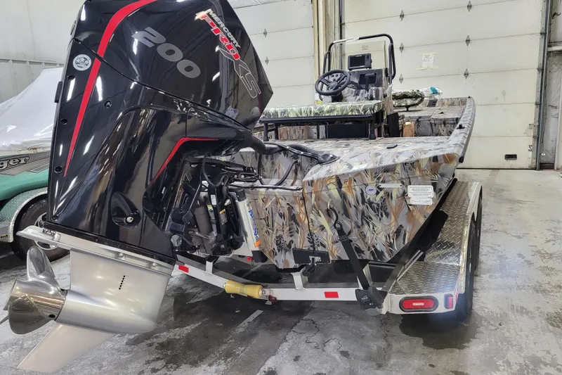 Slide: The Image of 2025 Ranger RB210 boat with camo design and powerful Mercury Pro XS engine in a garage. - 3