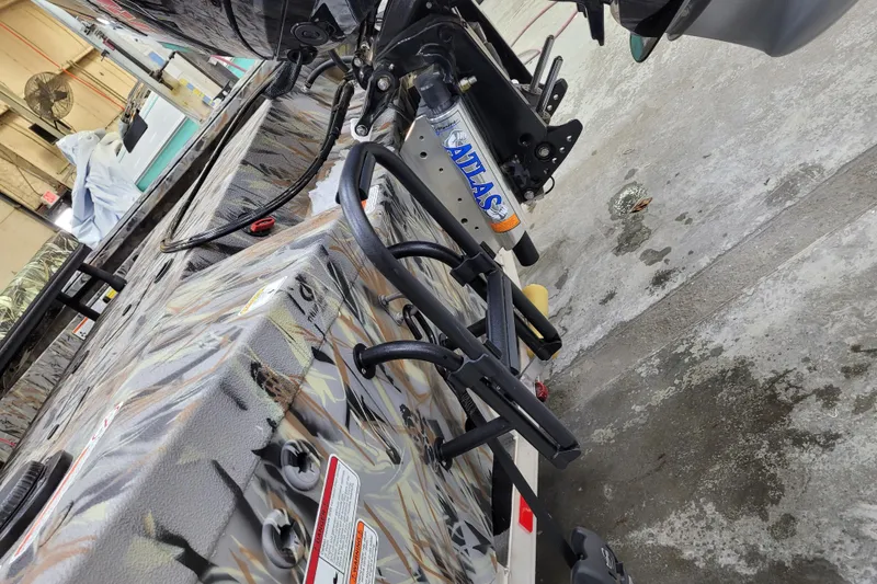 Slide: The Image of 2025 Ranger RB210 boat with camo design and Atlas hydraulic jack plate in a workshop. - 4