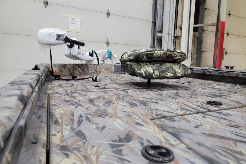 Slide: The Image of 2025 Ranger RB210 boat interior with camo seats and trolling motor in a garage. - 6