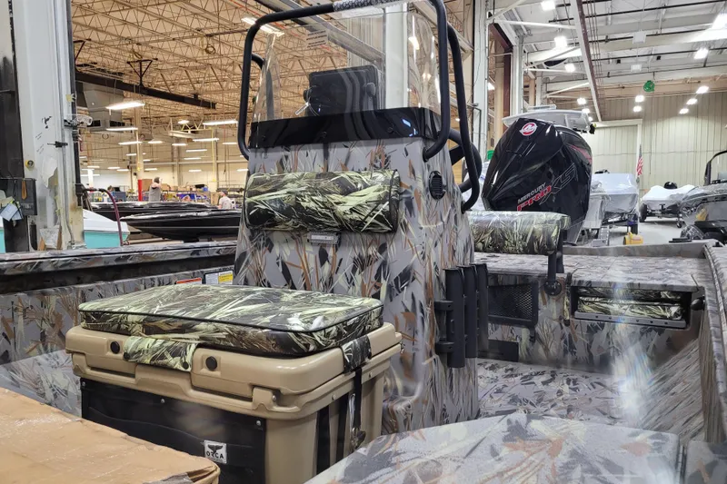 Slide: The Image of 2025 Ranger RB210 boat interior with camouflage seating and powerful outboard motor in a factory setting. - 7