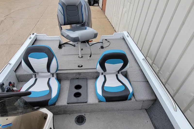 Slide: The Image of 1999 Ranger 107 Cherokee boat interior with blue and white seats, docked beside a building. - 19