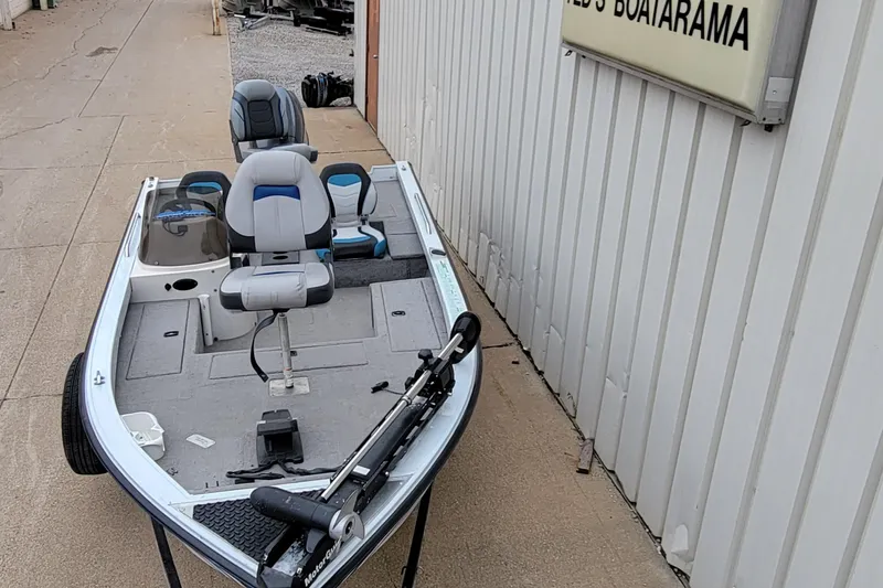 Slide: The Image of 1999 Ranger 107 Cherokee fishing boat with seating and trolling motor, parked outside. - 2