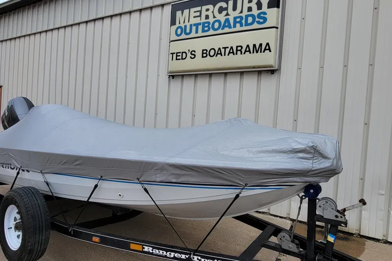 Slide: The Image of 1999 Ranger 107 Cherokee boat covered, parked at Ted's Boatarama, Mercury Outboards sign visible. - 22