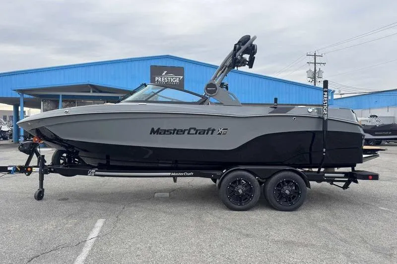 The Image of 2026 MasterCraft XT23 boat on trailer at dealership, showcasing sleek design. - 1