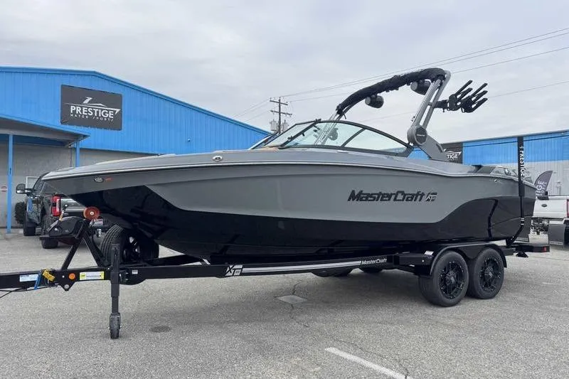 Slide: The Image of 2026 MasterCraft XT23 boat on trailer at Prestige dealership, gray and black design. - 4