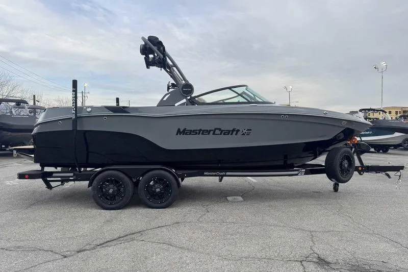 Slide: The Image of 2026 MasterCraft XT23 boat on trailer, parked outdoors, side view. - 6