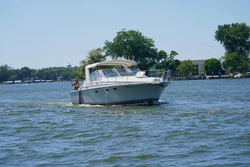 Slide: The Image of 1984 Trojan 11 Meter Express boat cruising on a scenic lake with trees in the background. - 2