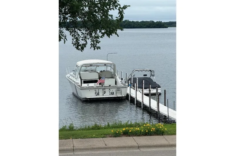 Slide: The Image of 1984 Trojan 11 Meter Express boat docked on a calm lake with American flag. - 6