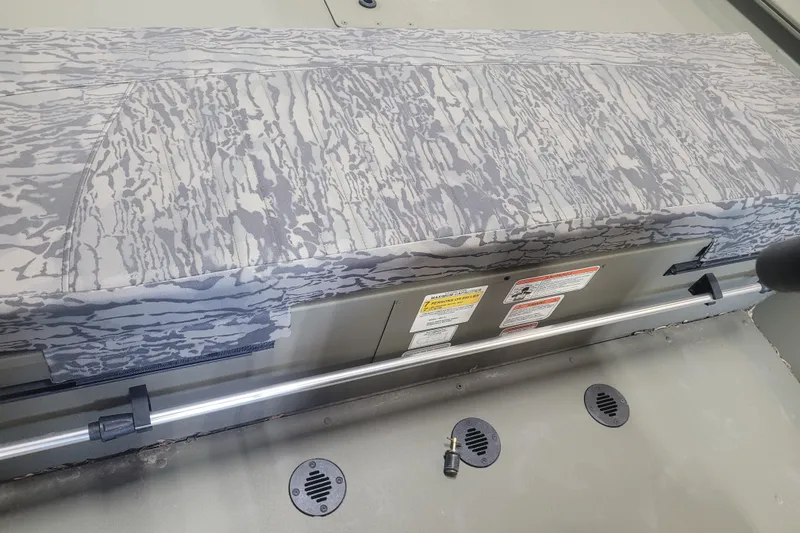 Slide: The Image of 2026 Tracker Grizzly 1860 CC boat interior with camo seat and safety labels. - 10