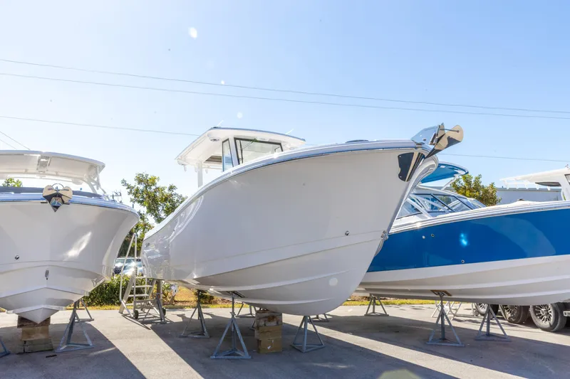 The Image of 2026 Edgewater 285CC boats displayed outdoors on stands under clear blue sky. - 0