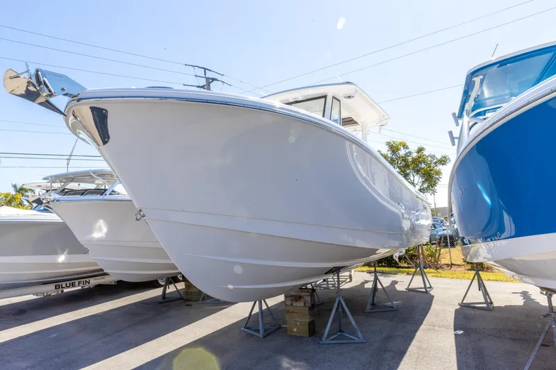 Slide: The Image of 2026 Edgewater 285CC boat displayed outdoors on stands, sunny day. - 10