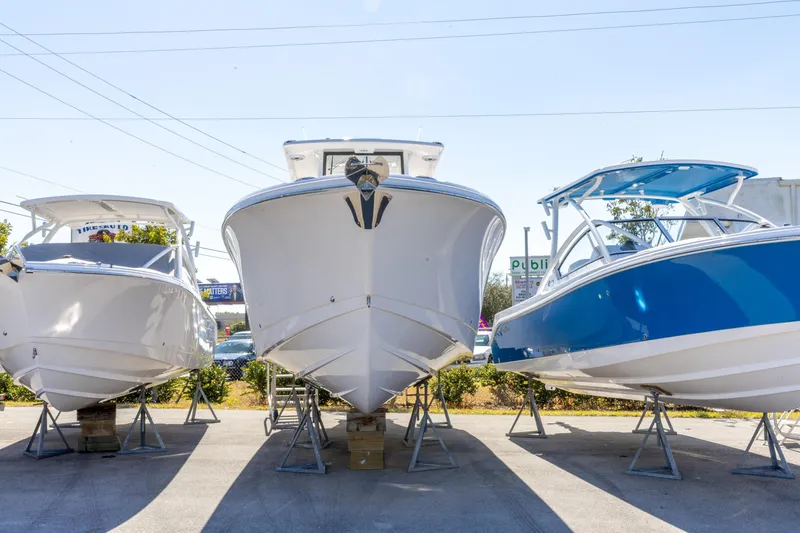 Slide: The Image of 2026 Edgewater 285CC boat displayed between two other boats on stands. - 27
