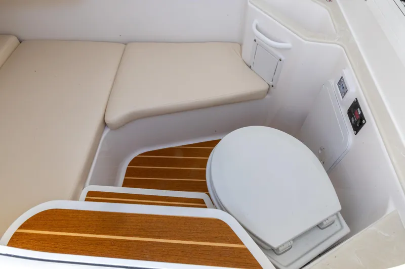 Slide: The Image of 2026 Edgewater 285CC boat interior with cushioned seating and marine toilet. - 3
