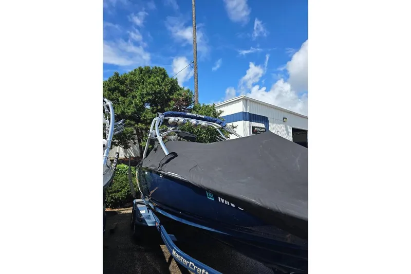 Slide: The Image of 2006 MasterCraft X-45 boat with cover, parked outdoors under a clear blue sky. - 7