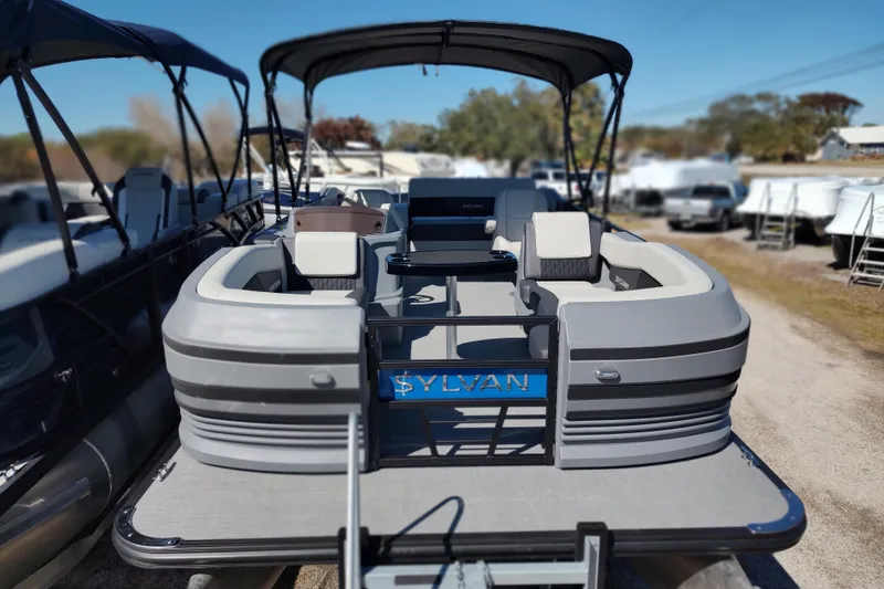 Slide: The Image of 2026 Sylvan R-22 pontoon boat with spacious seating and canopy, parked outdoors. - 4