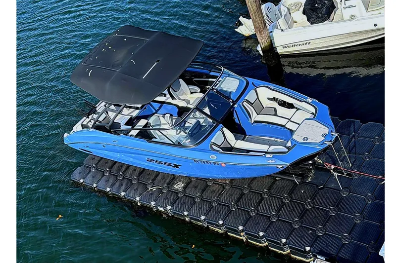 Slide: The Image of 2024 Yamaha 255XE boat docked on water, featuring sleek blue design and spacious seating. - 3