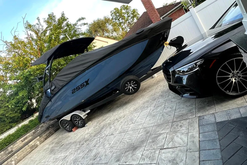 Slide: The Image of 2024 Yamaha 255XE boat on trailer beside luxury car in driveway. - 5