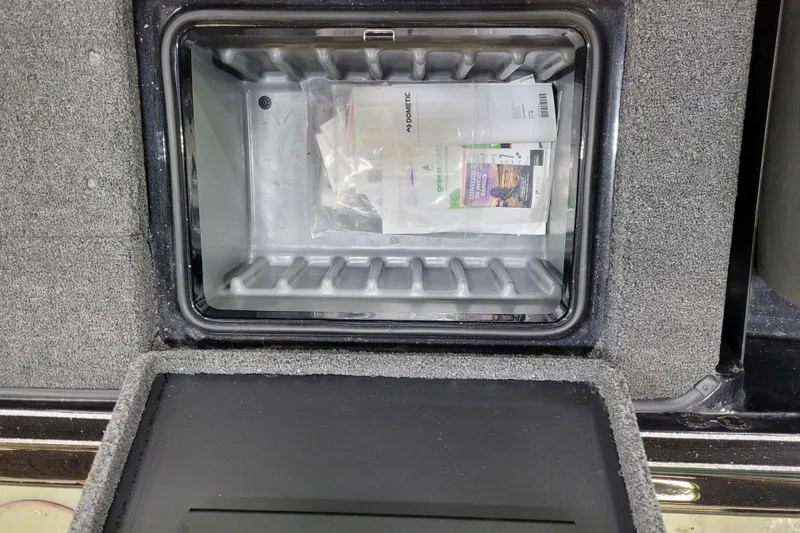 Slide: The Image of Open storage compartment in 2025 Triton 21XP boat, containing documents and packaging. - 12
