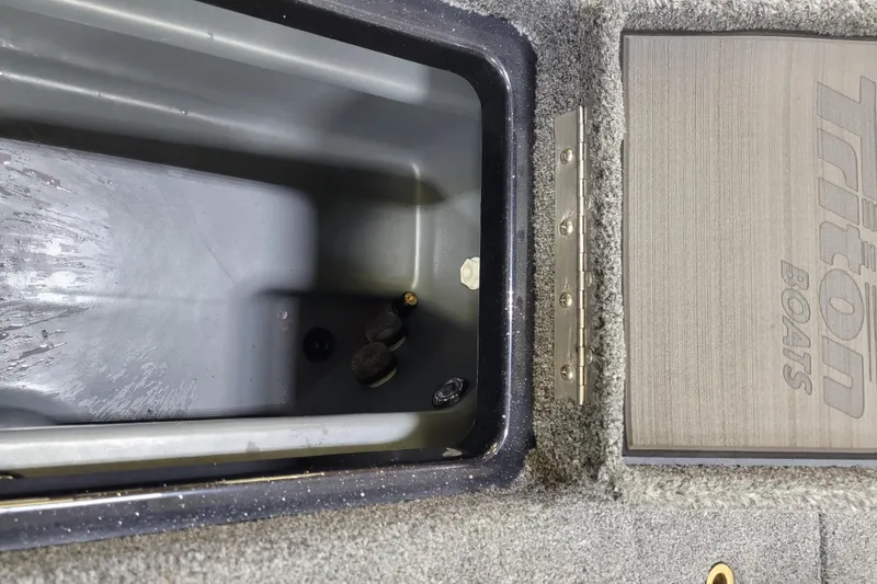 Slide: The Image of Open storage compartment in 2025 Triton 21XP boat, featuring durable interior and Triton branding. - 14