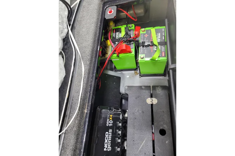 Slide: The Image of 2025 Triton 21XP boat battery compartment with green batteries and NOCO Genius charger. - 17