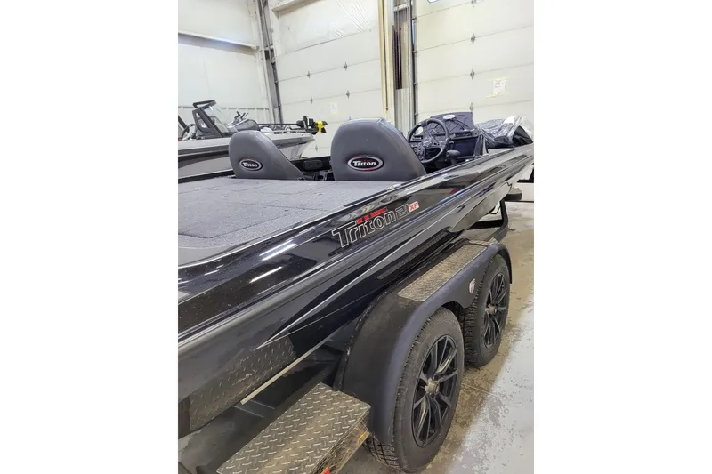 Slide: The Image of 2025 Triton 21XP boat in garage, featuring sleek black design and dual seats. - 38