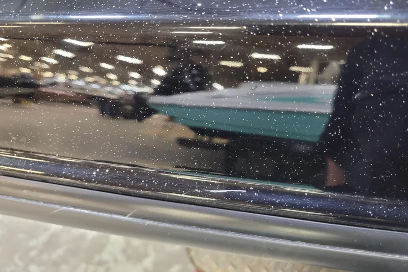 Slide: The Image of 2025 Triton 21XP boat with a glossy, speckled black finish in a showroom. - 45